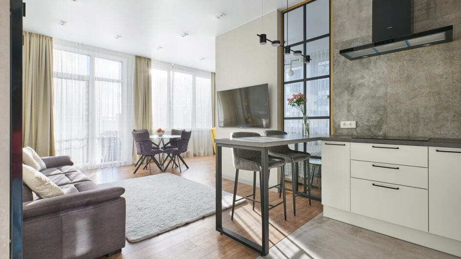 Apartamento com cozinha e sala integrada e janelas com cortinas brancas