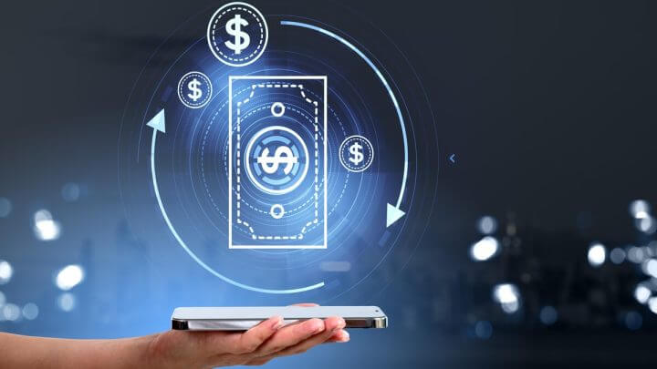 Mão feminina segurando um celular com a ilustração de uma nota de dólar em cima dele