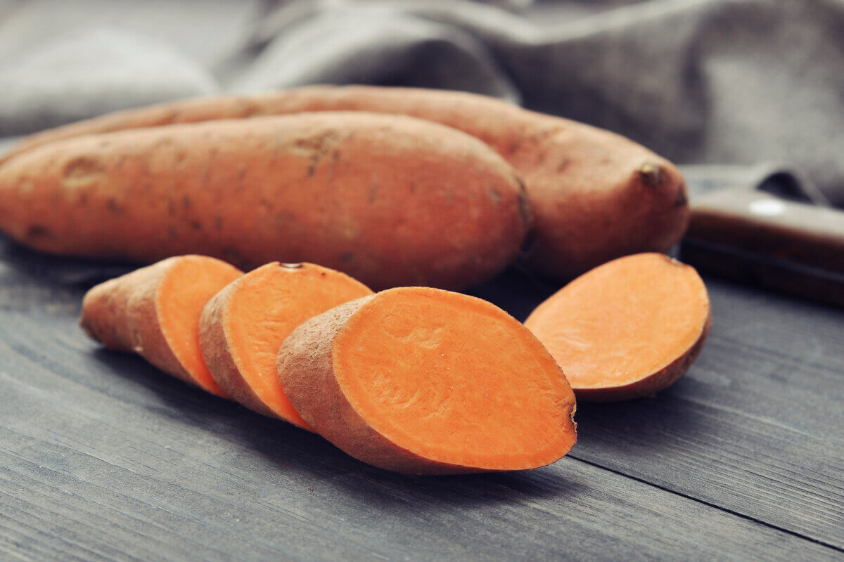 Batata-doce em cima de uma mesa de madeira com rodelas cortadas