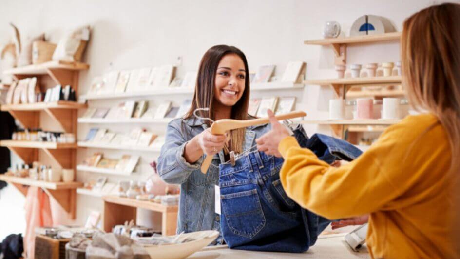 Assistente de vendas atendendo cliente em loja independente de roupa