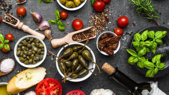 Mesa com tomate, azeitona, vinho e grãos espalhados