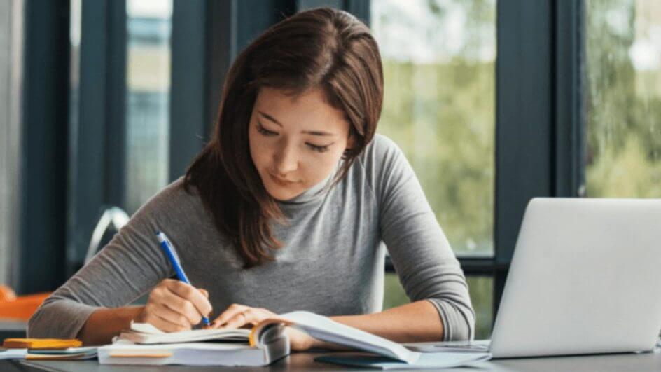 Jovem estudando escrevendo em caderno