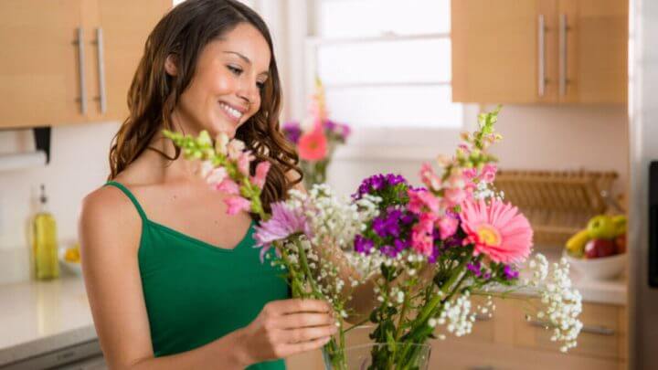 Mulher organizando flores em casa, feliz e alegre