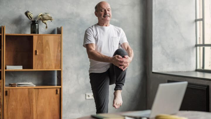 Homem de meia idade praticando pilates em uma sala de estar