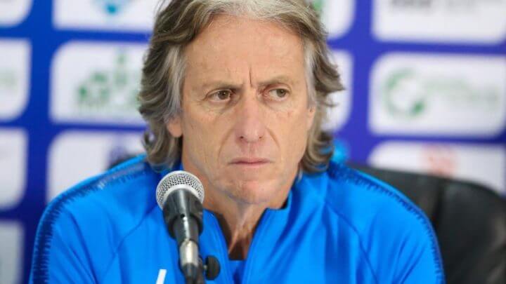 Imagem mostra Jorge Jesus vestido de camisa azul e um microfone na frente
