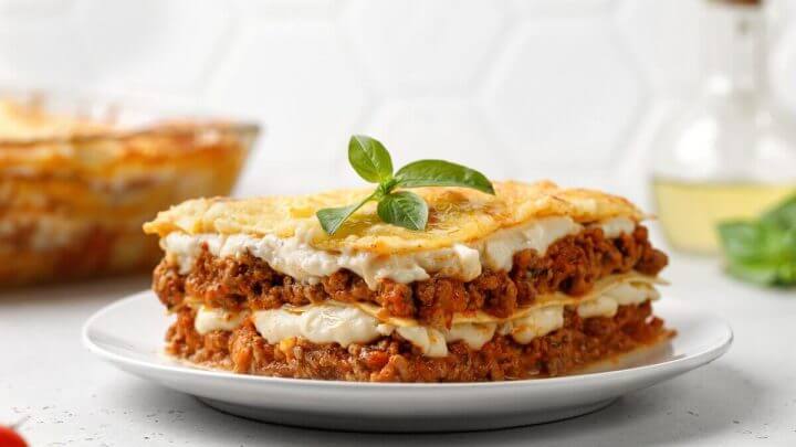 Lasanha com carne moída e molho branco em cima de um prato branco