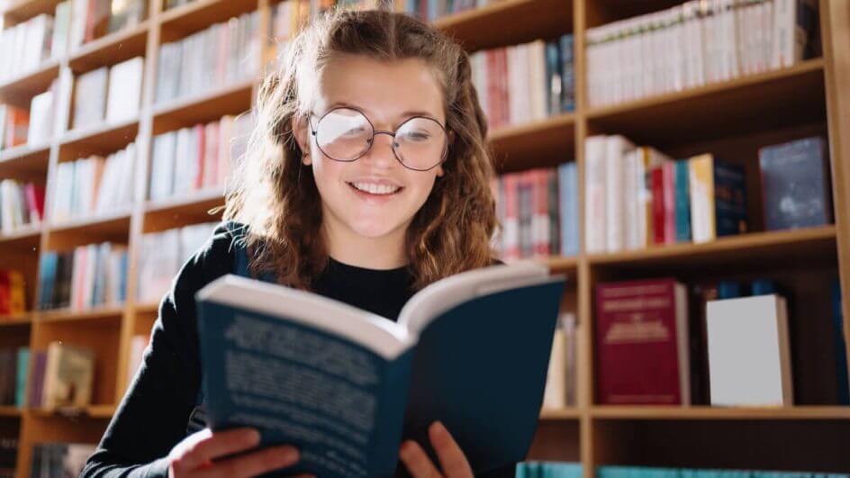 Garota lendo livro em uma biblioteca