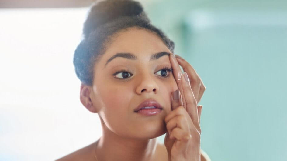 Mulher colocando as lentes de contato em frente ao espelho