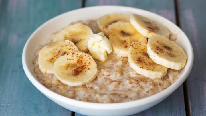 Mingau de aveia com banana e canela dentro de um recipiente branco