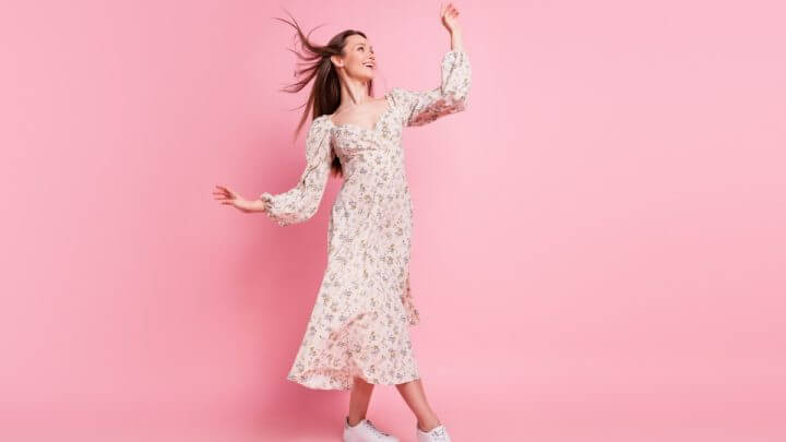 Mulher com vestido florido em frente a um fundo rosa