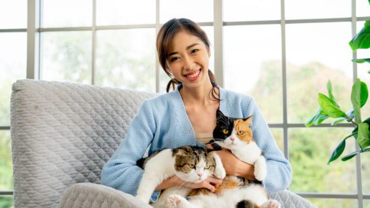 Mulher segurando dois gatos