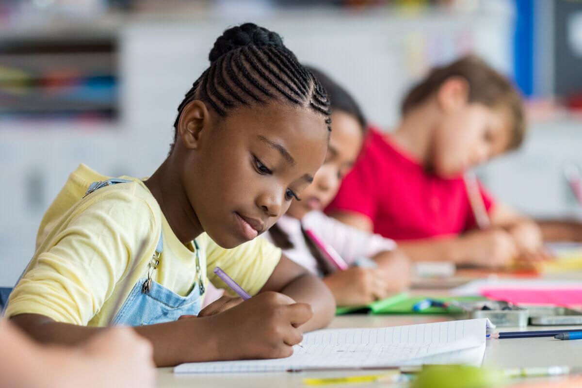 Menina sentada escrevendo em um caderno
