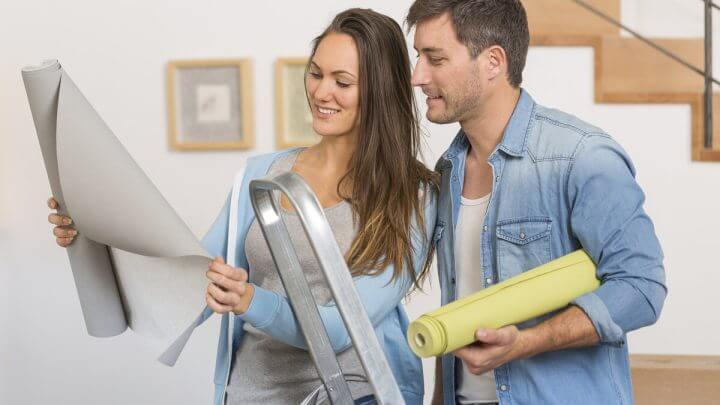 Mulher e homem olhando para um projeto de decoração e sorrindo