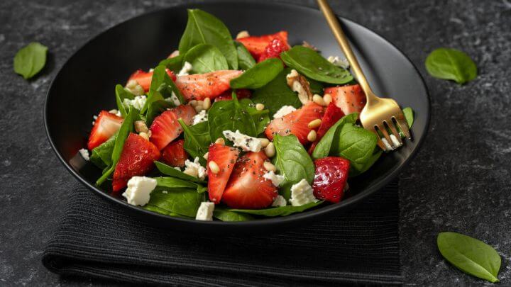 Prato preto com salada de espinafre com morango e queijo feta