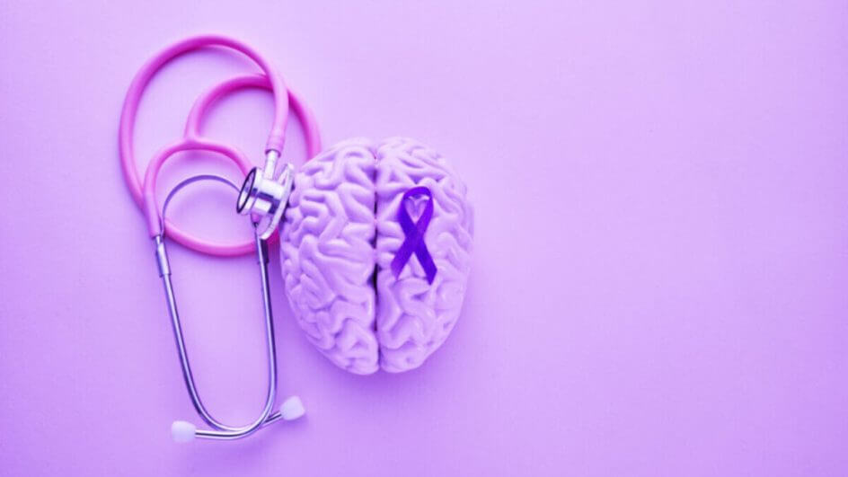 Objetos roxos como estetoscópio, cérebro e faixa para representar o mês de conscientização do Alzheimer