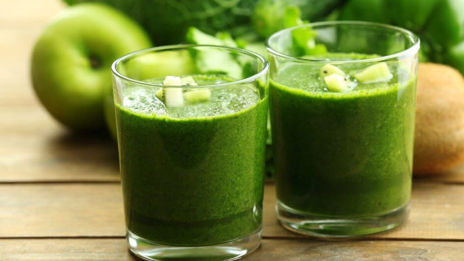 Suco verde em um copo transparente decorado com pedaços de kiwi