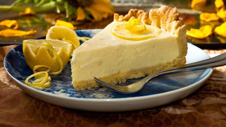 Pedaço de torta de limão em cima d eum prato branco e azul