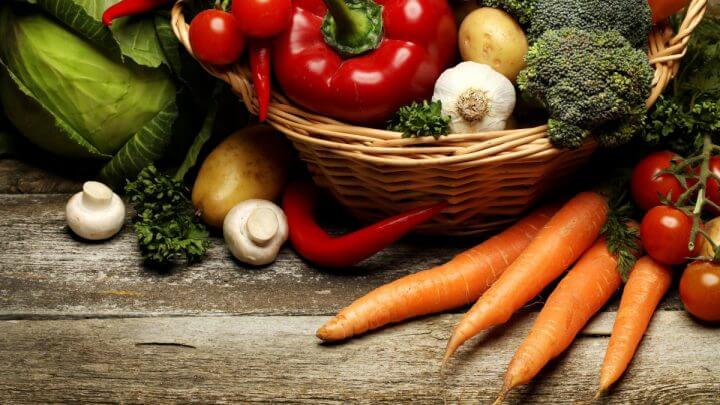 Vários alimentos naturais em uma cesta, tais como tomate, cenoura, alho, batata, brócolis, pimentão e mais