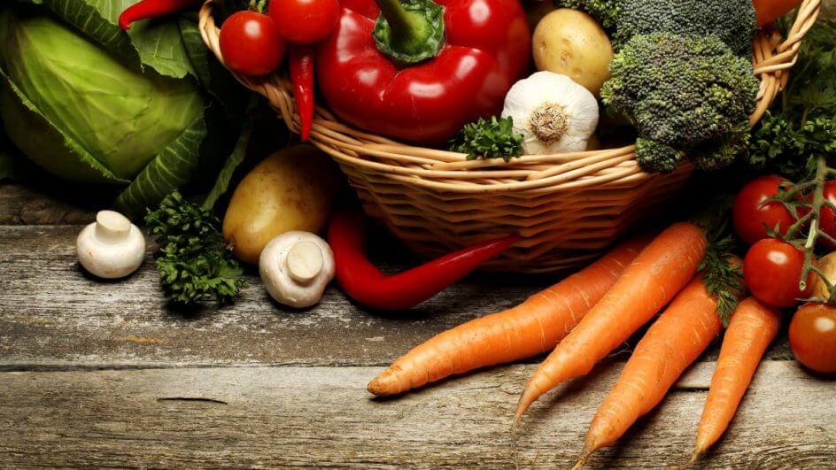 Vários alimentos naturais em uma cesta, tais como tomate, cenoura, alho, batata, brócolis, pimentão e mais