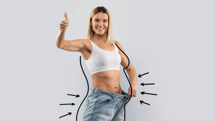 Mulher loira usando calça larga, demonstrando a grande perda de peso