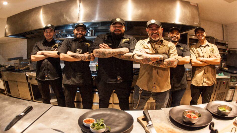 Chef Henrique Fogaça e outros cinco homens de sua equipe na cozinha de braços cruzados