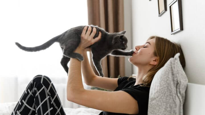 Garota de pijama segurando um gato preto nos braços