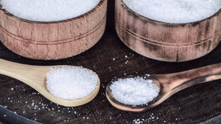 Recipientes e colheres de madeira com sal e açúcar