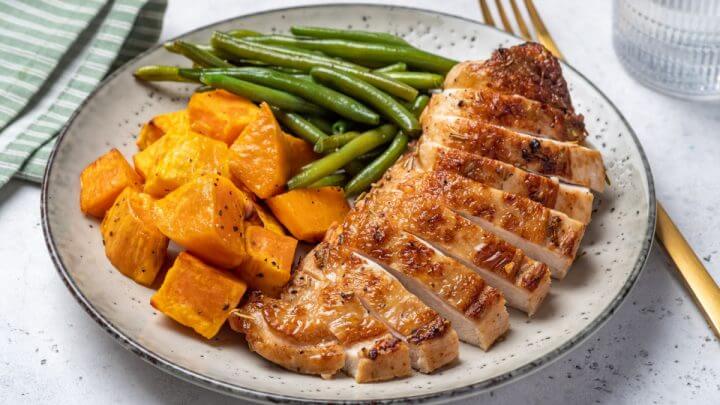 Frango assado com batata-doce laranja e salada de vagem em prato