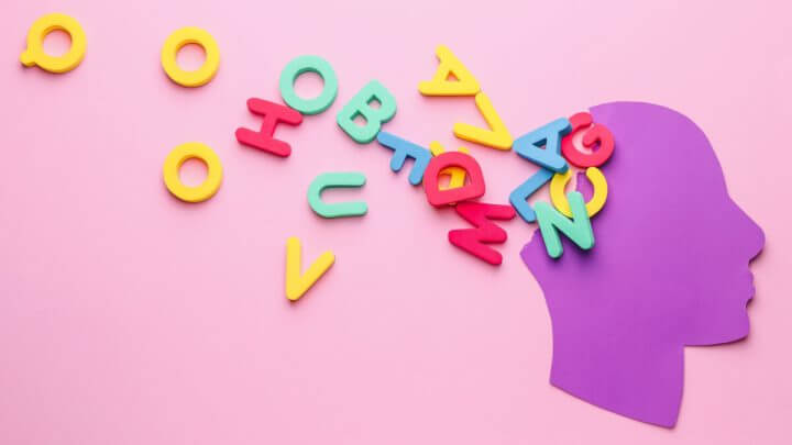 Ilustração de cabeça humana de papel com letras na cor de fundo, que é rosa