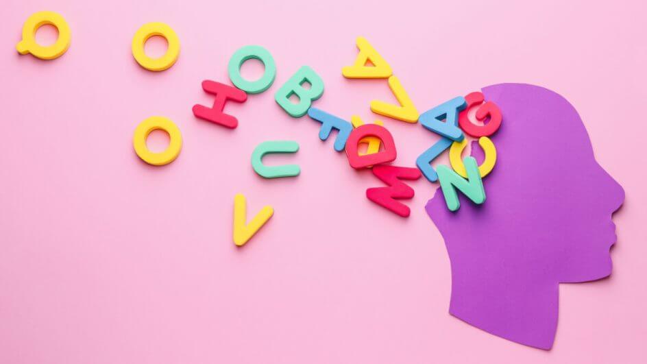 Ilustração de cabeça humana de papel com letras na cor de fundo, que é rosa