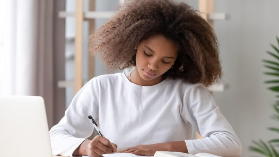 Menina vestindo blusa branca sentada estudando