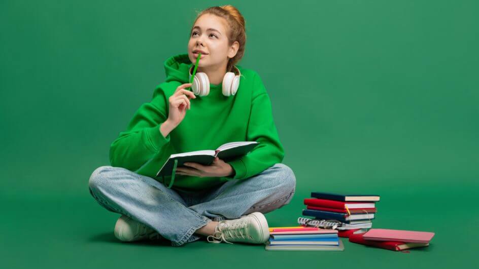 Menina sentada estudando com livros ao lado