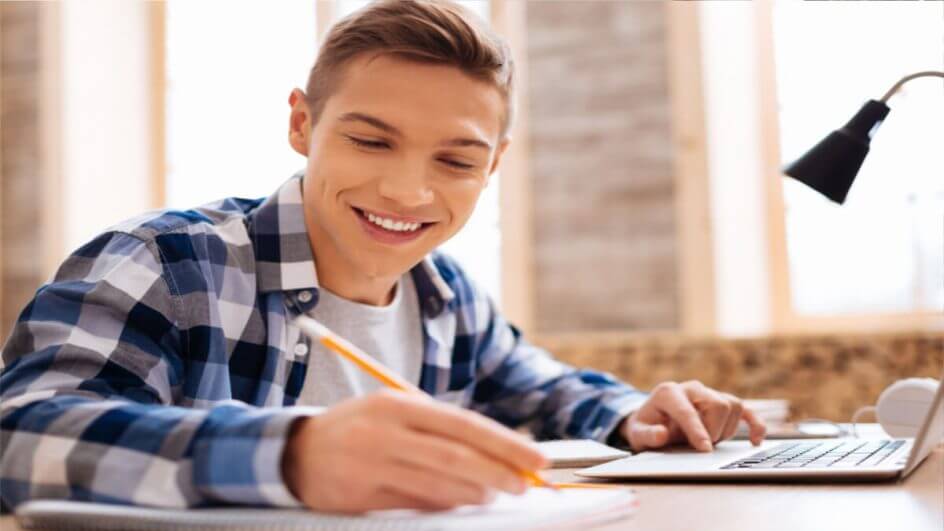 Menino de blusa xadrez sorrindo e estudando
