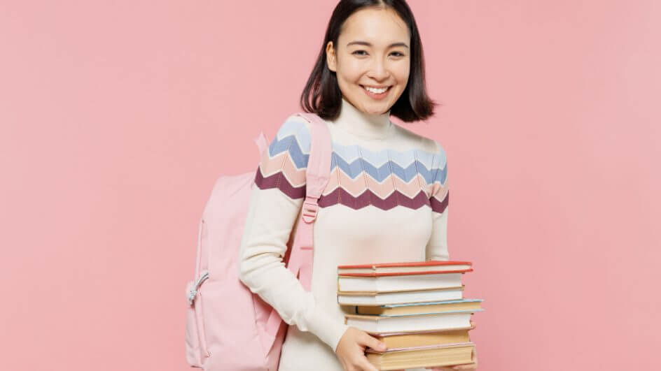 Garota adolescente segurando livros e com mochila no ombro