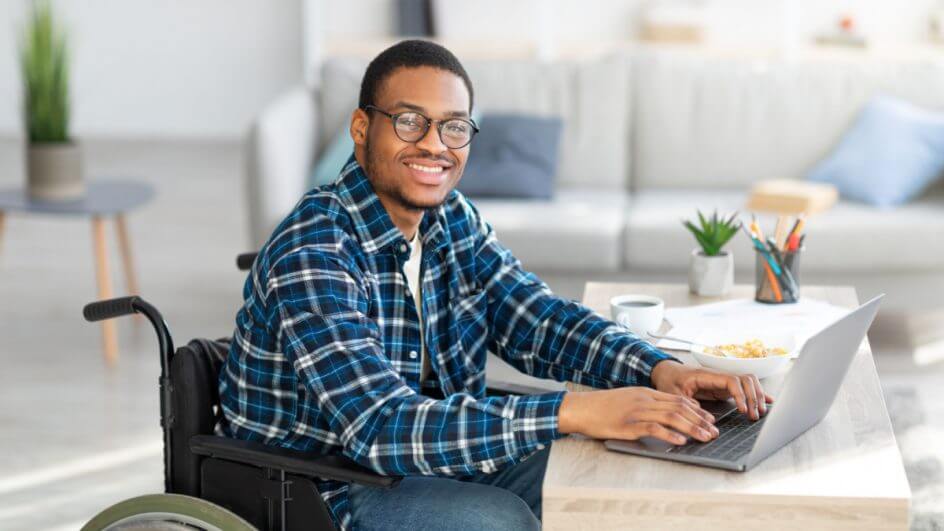 Homem em cadeira de rodas mexendo em notebook