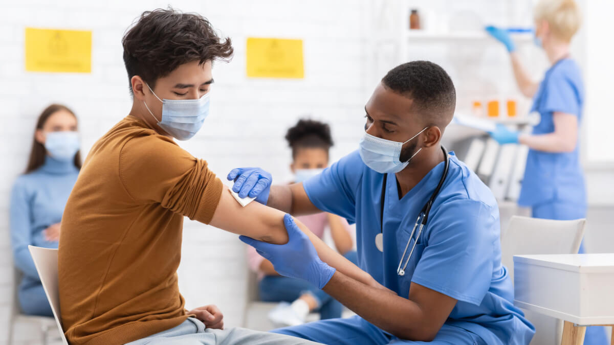 Homem sendo vacinado por enfermeiro em clínica médica