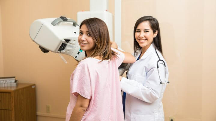Médica e paciente em uma sala realizando mamografia