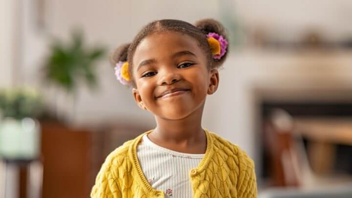 Menina sorrindo com cabelo preso e flores no cabelo