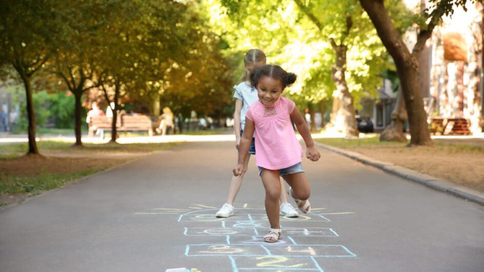Duas meninas na rua brincando de pular amarelinha