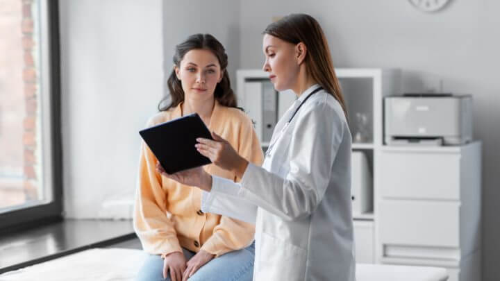 Mulher sendo atendida por médica em consultório