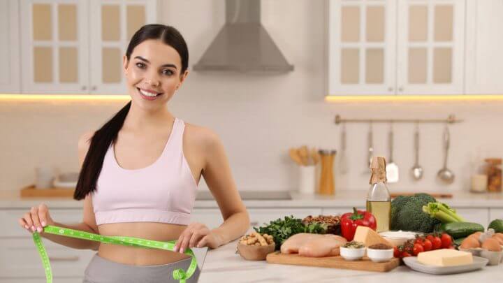 Mulher em cozinha com fita medindo cintura