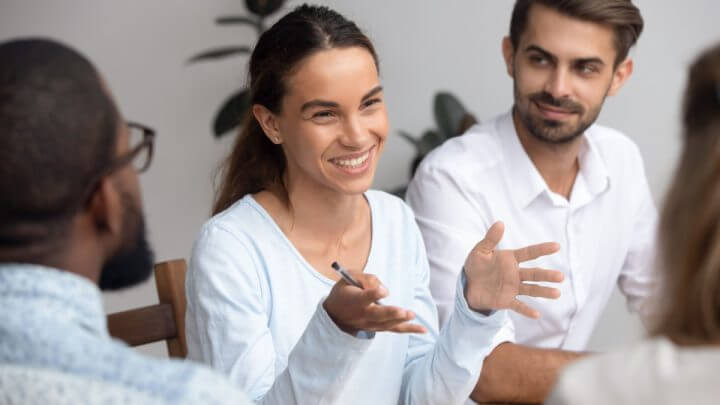 Mulher sorrindo e falando no meio de outras pessoas