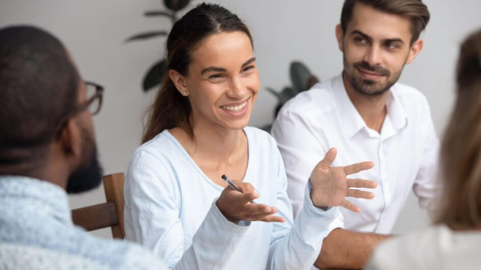 Mulher sorrindo e falando no meio de outras pessoas