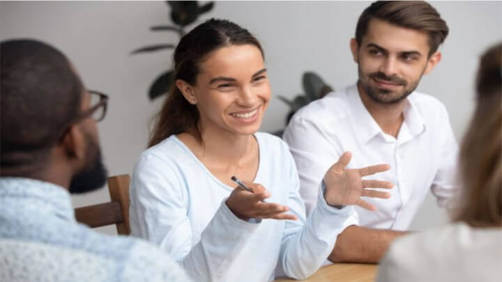 Mulher sorrindo e falando no meio de outras pessoas