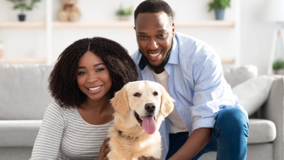 Mulher e homem abraçando um cachorro da raça golden retriever