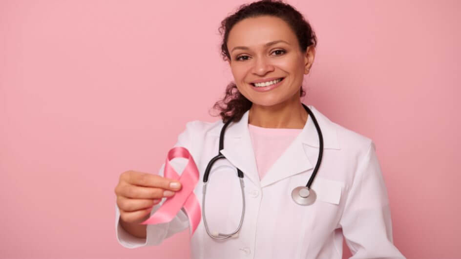 Médica segurando laço rosa, símbolo da campanha contra o câncer de mama