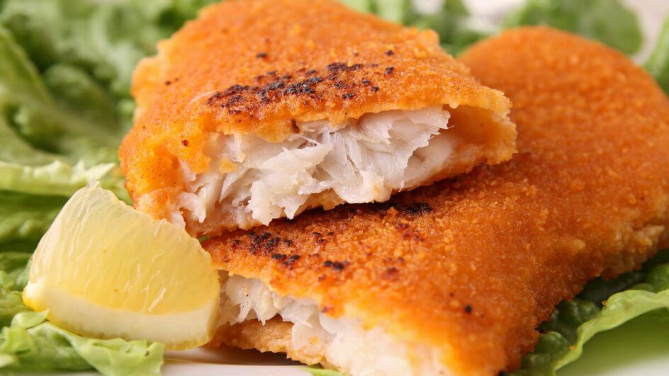 Peixe empanado em cima de um prato branco com salada