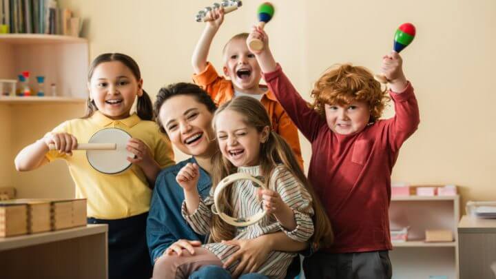 Professora com alunos felizes segurando instrumentos musicais