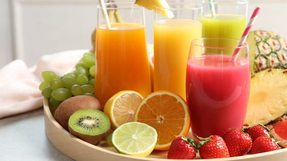 Na foto, quatro tipos de sucos com frutas cortadas