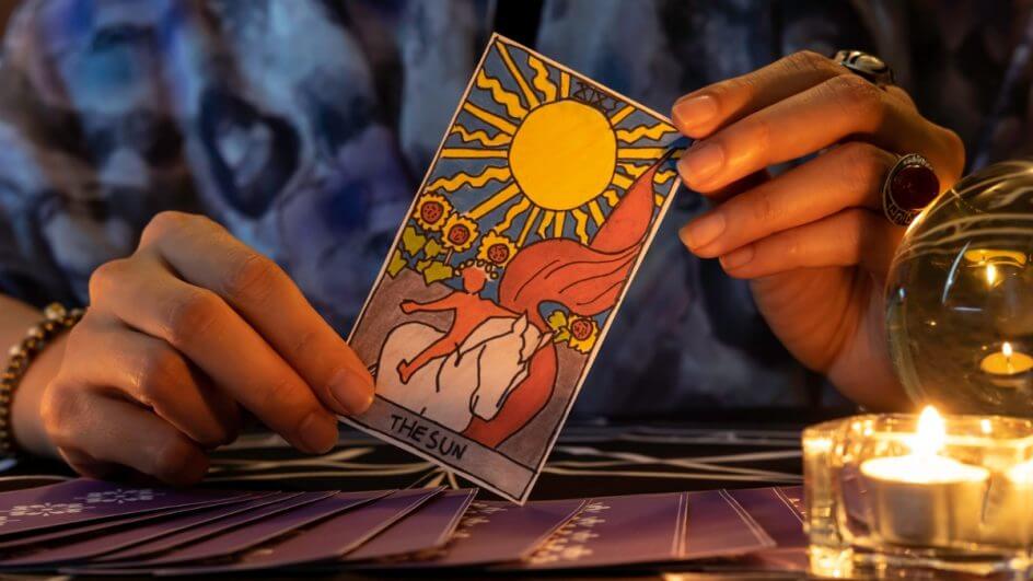 Mãos feminina segurando uma carta de tarot